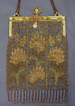 VINTAGE METALLIC BEADED FLORAL DESIGN HANDBAG: VINTAGE METALLIC BEADED FLORAL DESIGN HANDBAG WITH ENAMELED & JEWELED FRAME. BAG WITH FRINGE 10 1/4 X 6 1/2" (BEAD/FABRIC WEAK ON HINGED CORNERS; SEPARATING ALONG TOP EDGE OF FRAME)