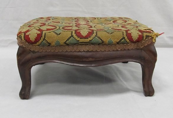 CARVED WALNUT FOOTSTOOL WITH NEEDLEPOINT: CARVED WALNUT FOOTSTOOL WITH NEEDLEPOINT UPHOLSTERY, 19TH CENTURY. HEIGHT 6"; TOP 12 X 13" (IMPERFECTIONS)
