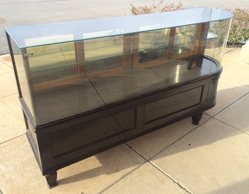 EBONIZED CARVED WOOD CURVED GLASS SHOWCASE: EBONIZED CARVED WOOD CURVED GLASS SHOWCASE. HEIGHT 38"; WIDTH 70"
