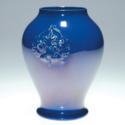 Cowan vase, oakleaf design, early, 6 1/4" : Early Cowan vase with molded decoration of oak leaves and acorns front and rear and covered with a rich blue delphinium glaze with some luster effect. Marked with the Cowan ink stamp logo. No crazing 