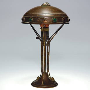 Austrian brass lamp, glass jewel insets, 15: Art Deco Austrian brass lamp, the shade inset with ruby and emerald green glass jewels, a rough jewel at the summit. The 8 inch shade is connected onto an open work tri-arm stem. Height is 15 inches.