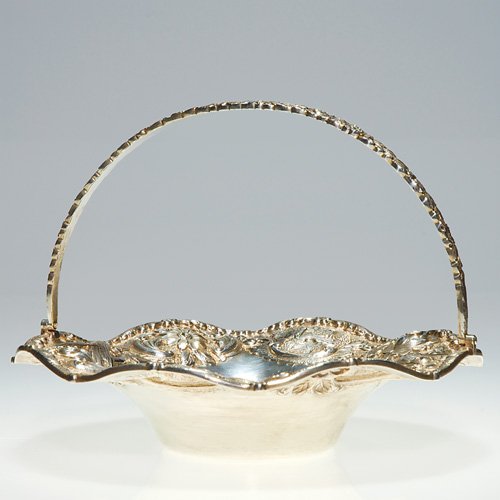 Loring Andrews 'Castle" handled basket. 5"X6 3/4": Sterling silver 'Castle" basket by Cincinnati based company, Loring Andrews. The ruffled border is neatly embossed with castles, flowers and birds, the hinged handle decorative with flowers. Height to