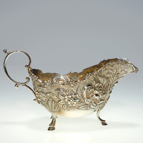 S Kirk & Son sterling sauce boat, hoof feet, 4: Good S. Kirk & Son silver sauce boat lofted on tripedal hoof feet. A garden variety of well detailed flowers in repousse are featured about the circumference. Flowers trim the rim. Height 4 inches, le