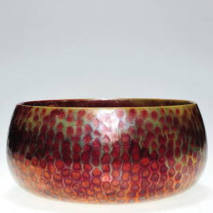 Zsolnay bowl in red with hammered surface, 3 1/2": Zsolnay bowl with red and gray iridescent glaze on a hammered surface. Marked with the white Zsolnay Pecs circular ink stamp logo. Height is 3 1/2 inches and diameter is 7 1/2 inches. Minor surface sc