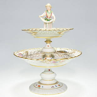 Meissen porcelain 2 tier compote, lady, 15": Meissen porcelain two tier compote at the top is a figure of a young lady with flower blossoms in her apron. The tiers are decorative with vignettes of flora and fauna on the top side and underside wh