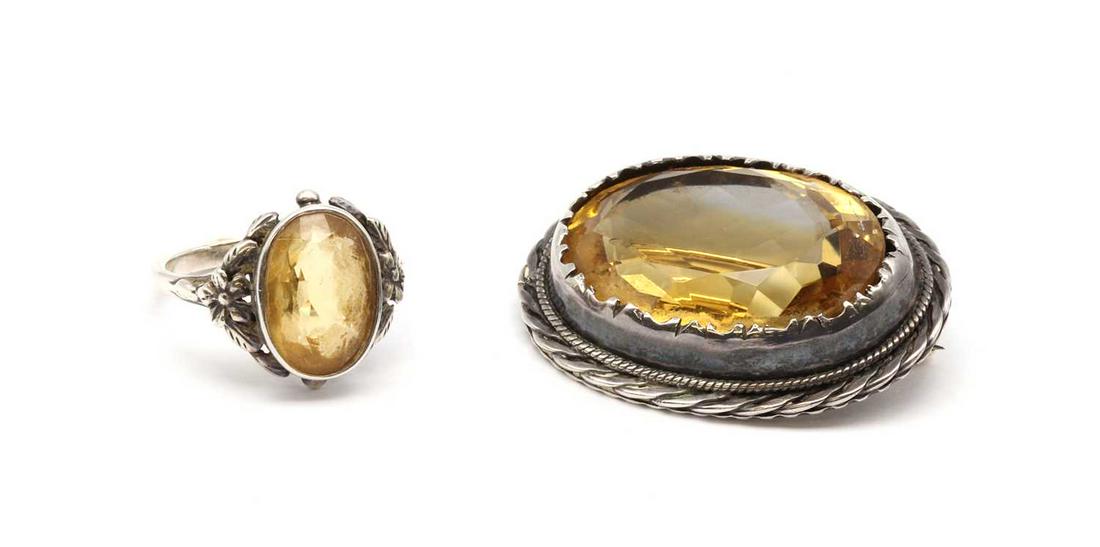 An Arts & Crafts silver single stone citrine ring,: An Arts & Crafts silver single stone citrine ring, A silver single stone citrine ring, attributed to Bernard Instone, the oval mixed cut citrine, rub set, to openwork foliate surround with engraved de