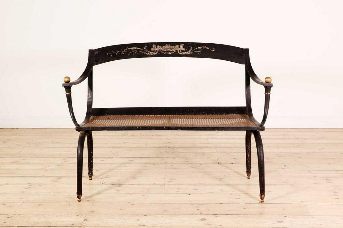 A painted settee in the manner of Jean Joseph Chapuis,: A painted settee in the manner of Jean Joseph Chapuis, A painted settee in the manner of Jean Joseph Chapuis, 19th century, the curved back with a classical motif, over open arms and a caned seat, rai