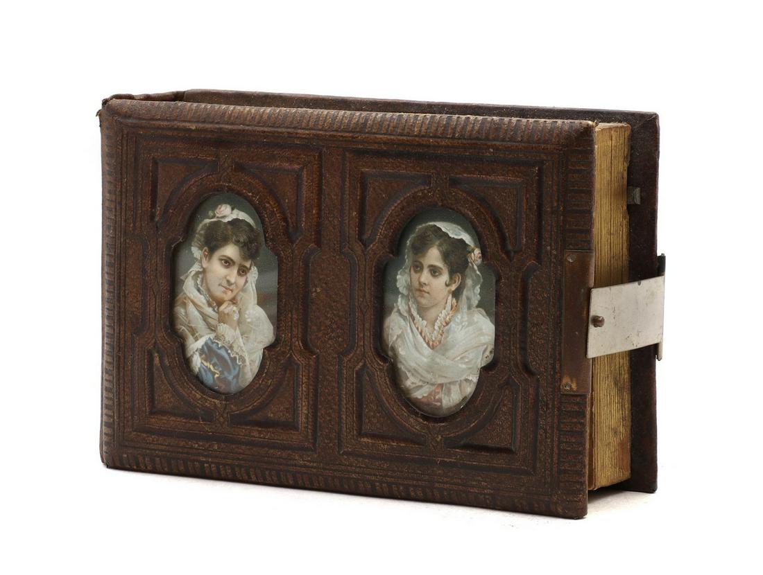 A Victorian musical photograph album,: A Victorian musical photograph album, A Victorian musical photograph album, the leather cover with a pair of printed portraits encloses 11 pages for photographs and the musical movement, 21cm long 14.