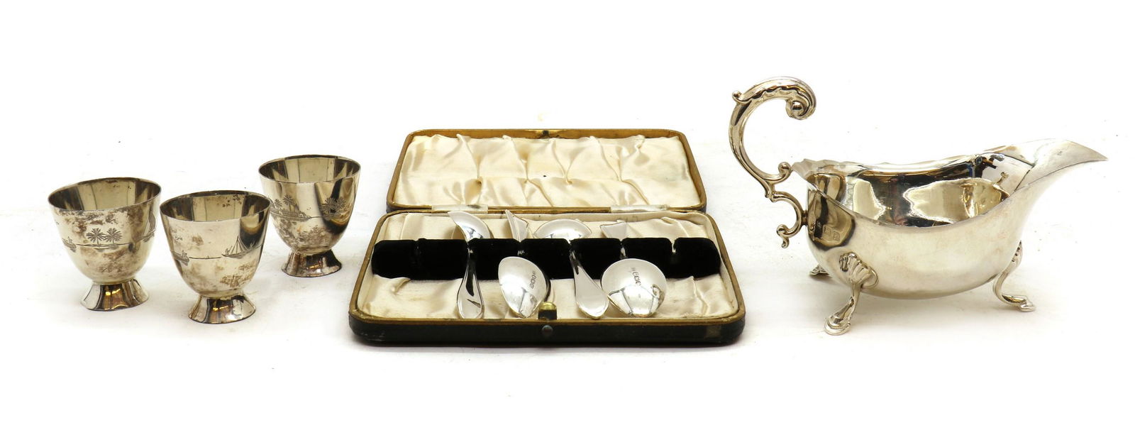 A silver sauceboat: A silver sauceboat A silver sauceboat, by S Blanckensee & Son Ltd, Birmingham 1938, with scroll acanthus topped handle, 14cm wide, together with three Iraqi silver egg cups, on domed feet, and a cased