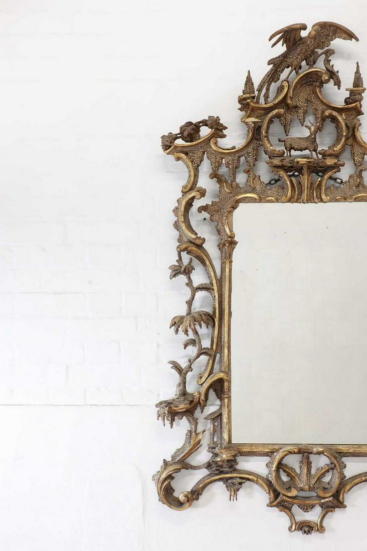 A carved giltwood pier glass in the manner of Thomas Johnson,: A carved giltwood pier glass in the manner of Thomas Johnson,probably 19th century, the elaborate rococo frame surmounted with ho-ho birds and a kid goat, with flowers and foliate scrolls, rockwork an
