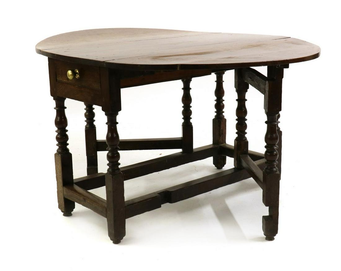 An oval oak gateleg table: An oval oak gateleg table An oval oak gateleg table, 18th century, fitted an end drawer with later brass handle, on turned and joint legs 164cm wide 107cm deep 70cm high Condition Report: Good deep pa