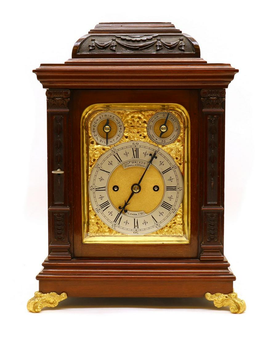 A George II-style mahogany mantel clock by John Walker of London: A George II-style mahogany mantel clock by John Walker of London A George II-style mahogany mantel clock by John Walker of London, c.1900, the case carved with swags and harebells, enclosing a twin-fu