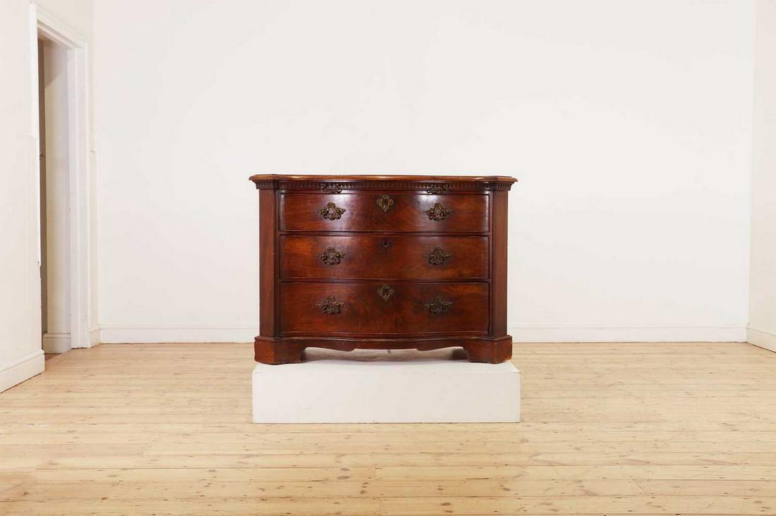 A George III mahogany serpentine commode,: A George III mahogany serpentine commode, A George III mahogany serpentine commode, c.1765, in the manner of Thomas Chippendale, with fluted frieze, brushing slide and cast bronze rococo handles, with