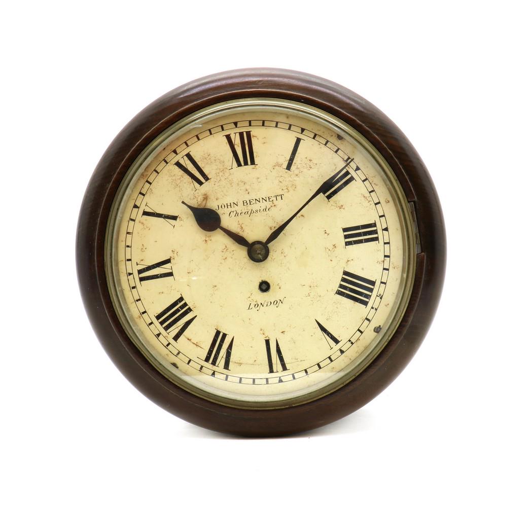 A Victorian fusee wall clock: A Victorian fusee wall clock A Victorian fusee wall clock, late 19th century, the white dial painted with black Roman numerals signed John Bennett, London, complete with pendulum and key 33cm diameter