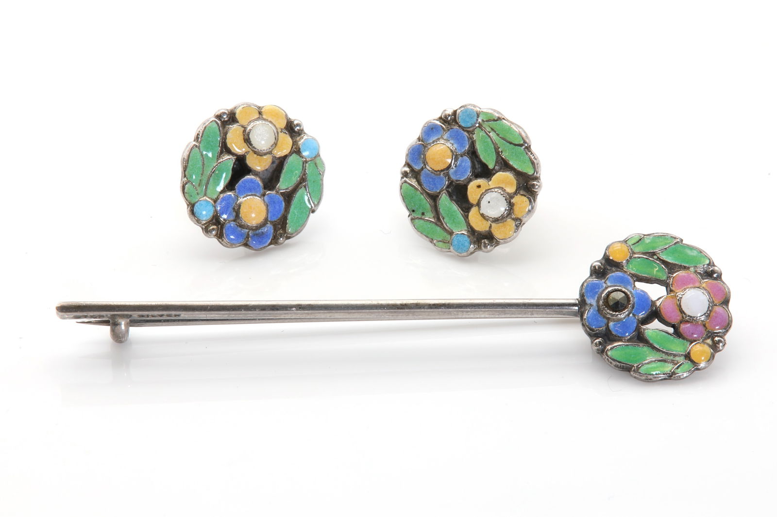 An Arts and Crafts floral bar brooch attributed to Bernard Instone,: An Arts and Crafts floral bar brooch attributed to Bernard Instone, An Arts and Crafts floral bar brooch attributed to Bernard Instone, the circular plaque designed as a cluster of flower heads and le