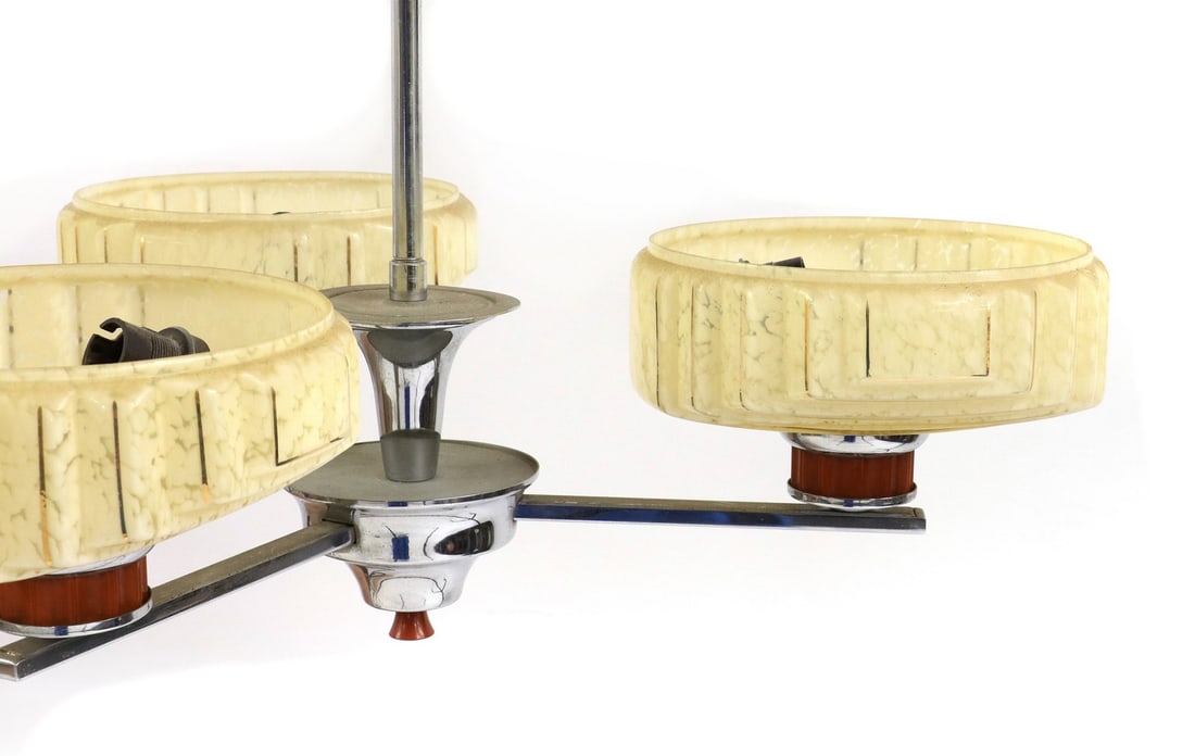 A suite of Art Deco light fittings: A suite of Art Deco light fittings A suite of Art Deco light fittings, comprising a chrome, bakelite and glass three branch chandelier, 53cm wide, 50cm high, and three wall lights, 26cm high (4) Condi