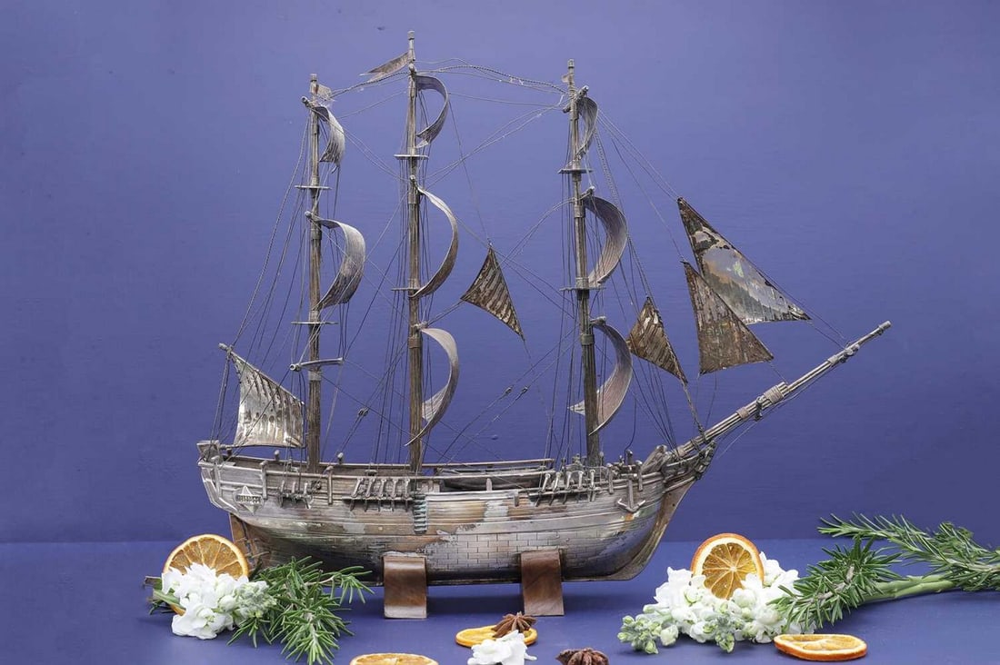 A white metal model of HMS Bounty,: A white metal model of HMS Bounty, A white metal model of HMS Bounty, 19th century, possibly Chinese, the three-masted ship in full sail, with abalone shell to the lifeboat interiors and raised on a t