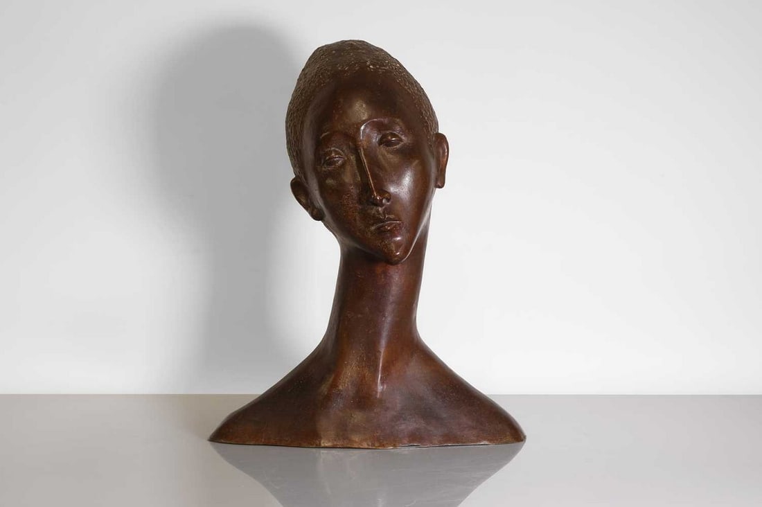 A Continental patinated bronze bust,: A Continental patinated bronze bust, c.1950, in the manner of Bernhard Hoetger, modelled as a woman with elongated features, signed to the shoulder with monogram 'R.S.', 46cm wide 30cm deep 50cm high