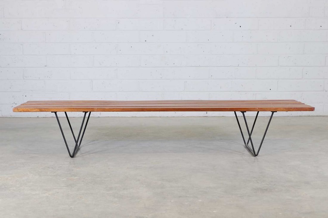 A mahogany and wrought steel bench,: A mahogany and wrought steel bench, designed in 1954 by Robin Day (1915-2010), with a slatted seat and a black steel stand, 183.5cm wide 45.5cm deep 32cm high Condition Report: Dusty and some wear to