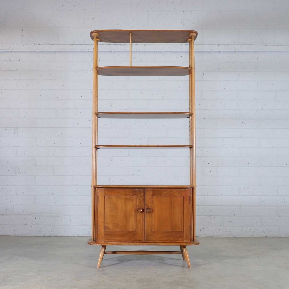 An Ercol 'Giraffe' room divider,: An Ercol 'Giraffe' room divider, with three shelves, two adjustable, over a cupboard, 85cm wide 40cm deep 191cm high, and a three-tier open bookshelf, 91cm wide 31cm deep 75.5cm high (2)
