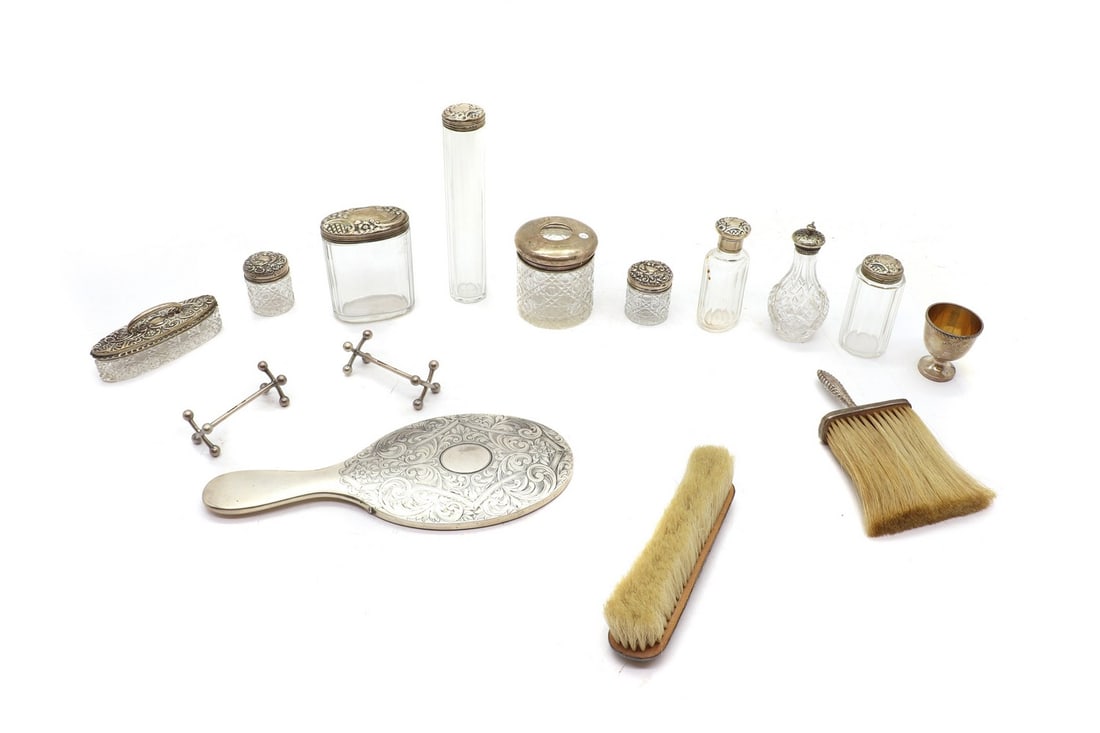 A collection of silver mounted dressing table items,: A collection of silver mounted dressing table items, to include a silver hand mirror, London 1927, a silver egg cup, by William Hutton & Sons Ltd, and a pair of silver knife rests, weighable 5.6ozt Co