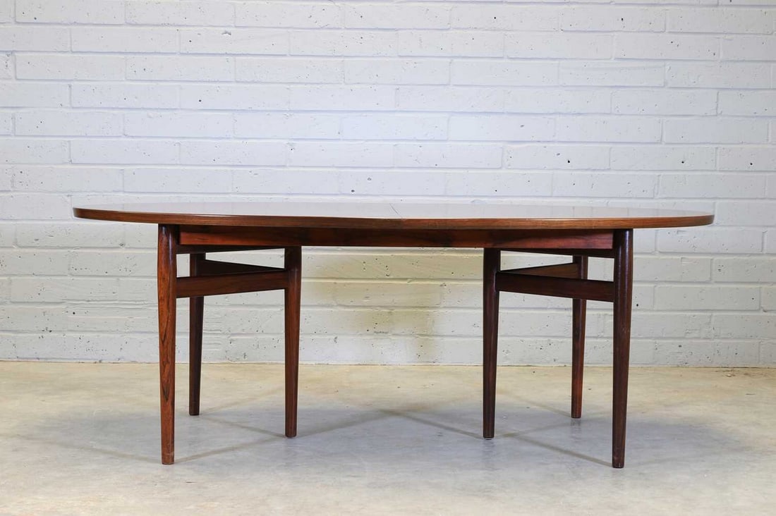 A Danish 'Model 227' extending rosewood dining table,: A Danish 'Model 227' extending rosewood dining table, designed by Arne Vodder for Sibast, the elliptical top raised to each side on three supports arranged in a chevron, 198cm wide 298cm extended 106c
