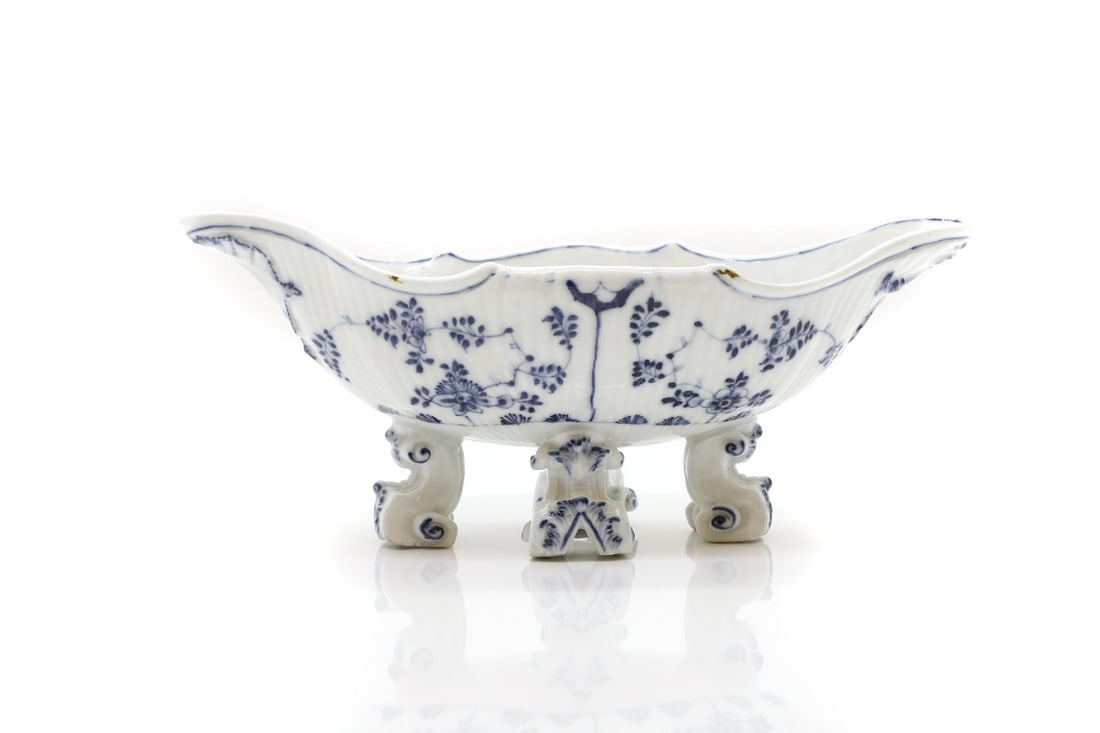 A Meissen porcelain sauceboat,: A Meissen porcelain sauceboat, 20th century, with a moulded body, with underglaze blue panels of flowers, on scrolled feet, crossed swords mark, 24.5cm wide Condition Report: Chips to the base support