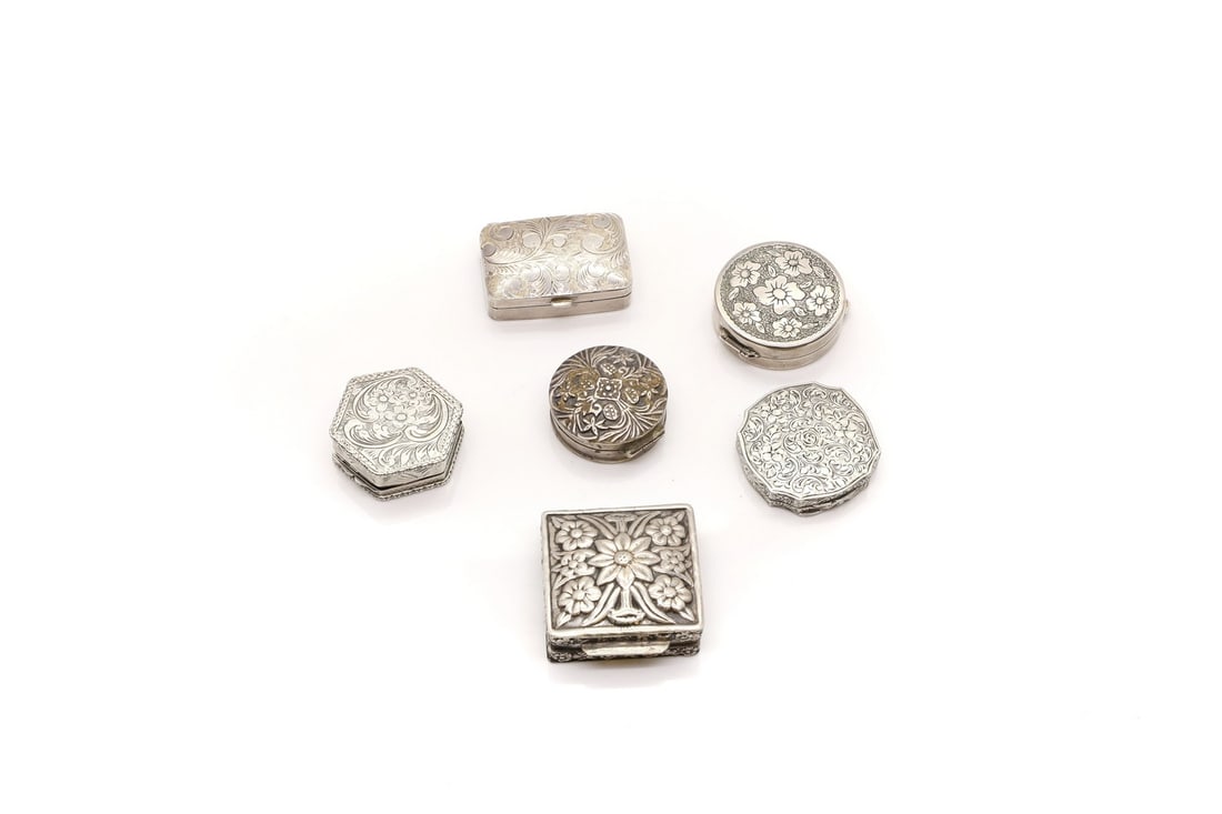 A group of six silver boxes: A group of six silver boxes all with floral embossed or engraved decoration, comprising a compact, with an internal mirror, 4cm wide, a hexagonal shaped pill box, marked 800, 4cm wide, a similar circu