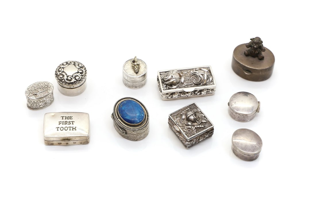 A group of silver pill boxes: A group of silver pill boxes to include an example by Vera Mary Honeker, London 1976, surmounted by a conch shell, 2cm diameter, a Mappin & Webb tooth box, surmounted by a teddy bear, 3.2cm wide, an e