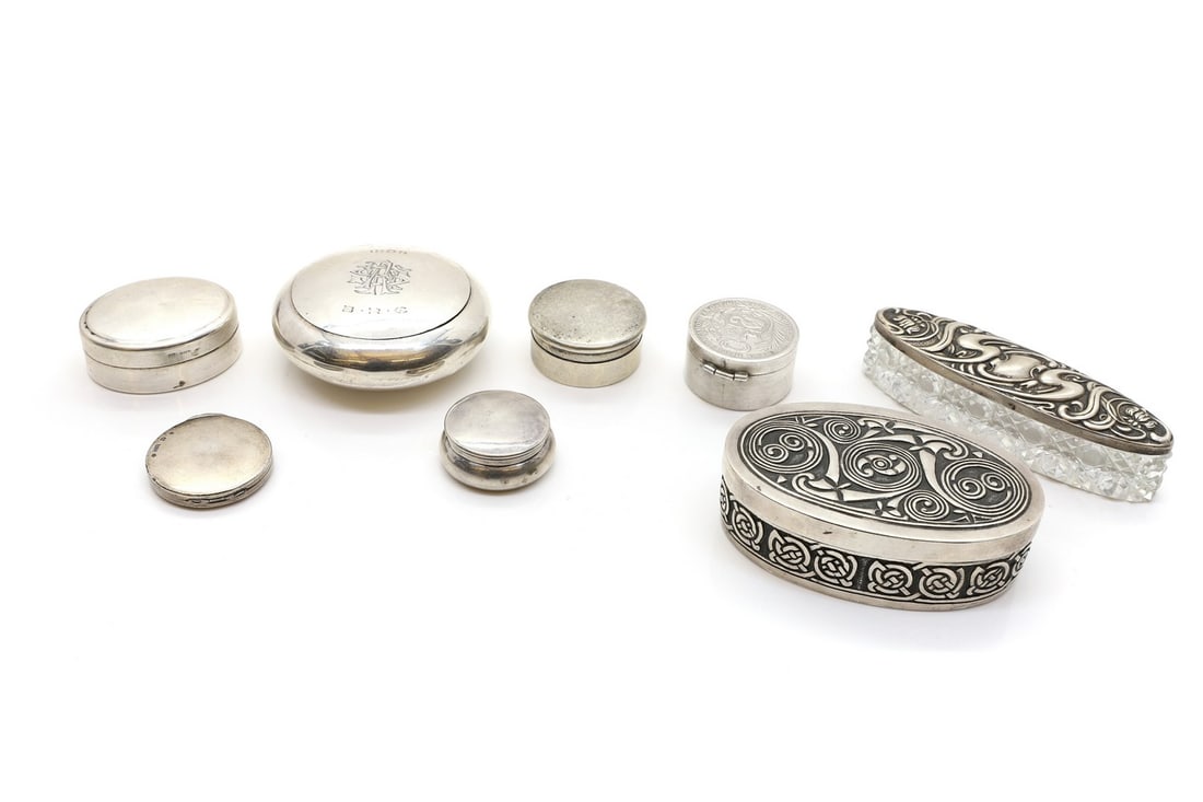 A collection of silver boxes: A collection of silver boxes comprising a compact, by William M Hayes, Birmingham 1903, with engraved initials, 7cm diameter, four various pill boxes, the largest 5cm wide, a Peruvian coin box, marked
