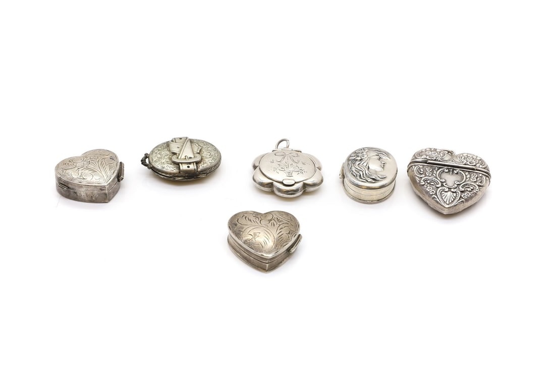 A group of silver pill boxes: A group of silver pill boxes comprising an example with An Art Nouveau style portrait of a lady, marked 925, 3.5cm high, two heart-form examples, marked 925, 3cm wide, a similar vesta case, marked 925
