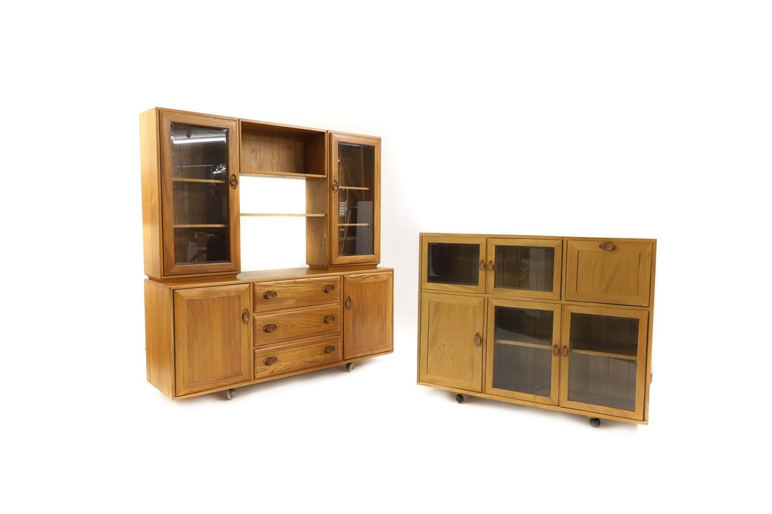 Two Ercol ash cabinets: Two Ercol ash cabinets the low cabinet with glazed cupboards, a fall front compartment, on castors, 122cm wide 32cm deep 96cm high; the other, with arrangement of drawers and cupboards below bevelled