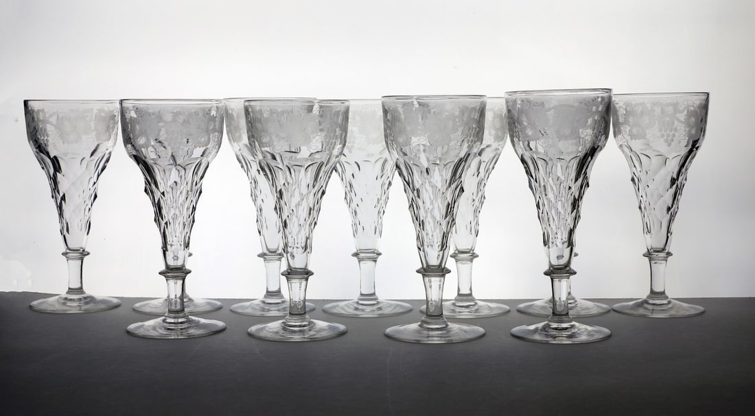 A collection of wine glasses,: A collection of wine glasses, c.1930s, in the manner of John Walsh Walsh, engraved with fruiting vine decoration, in three differing sizes, 10-13cm high together with champagne flutes, 16cm high (31)