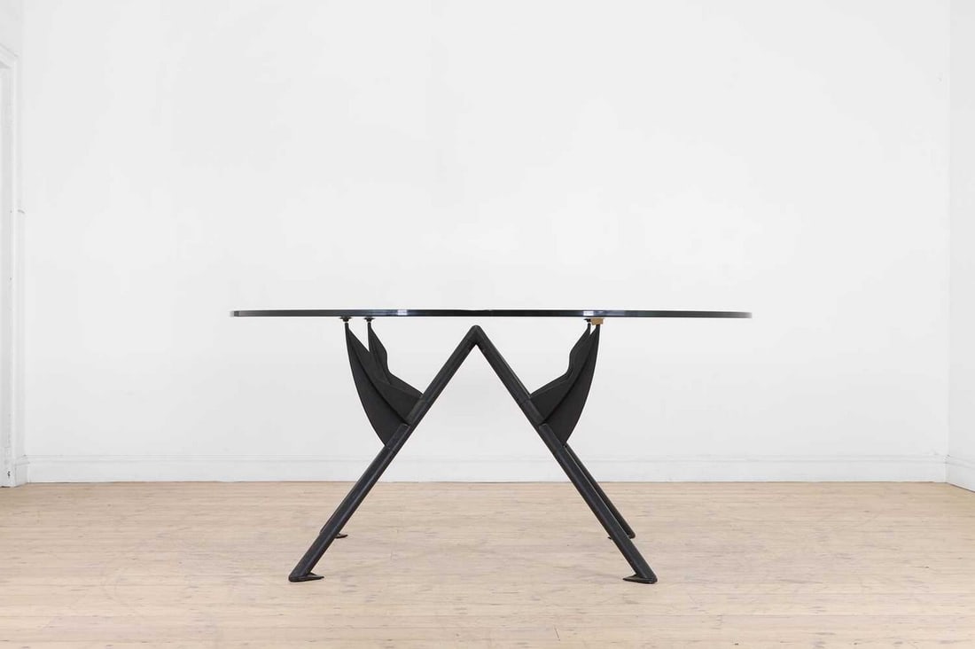 Philippe Starck (French, b.1949),: Philippe Starck (French, b.1949), a 'President M' table, c.1984, designed for Baleria Italia, the circular glass top over an angular black-painted aluminium base, cast 'Philippe Starck Baleri Italia 1