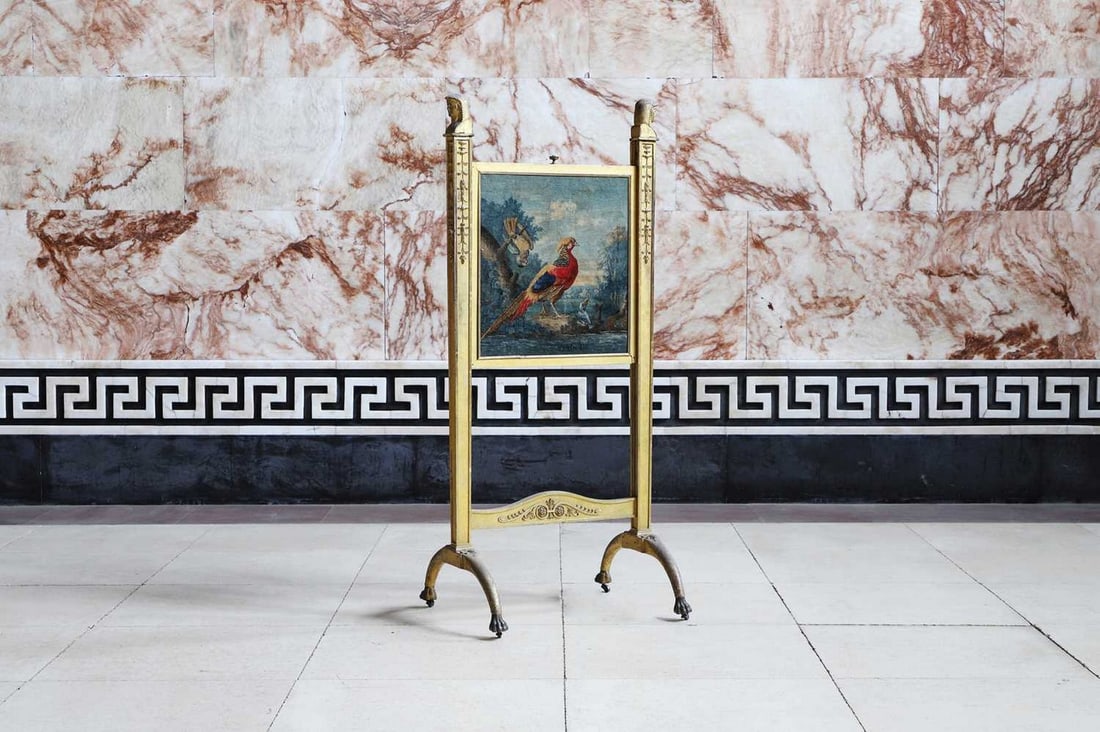 A Regency giltwood fire screen in the manner of Thomas Chippendale the Younger,: A Regency giltwood fire screen in the manner of Thomas Chippendale the Younger, first quarter of the 19th century, the uprights with Egyptian herm finials and carved with stylised harebells, holding a