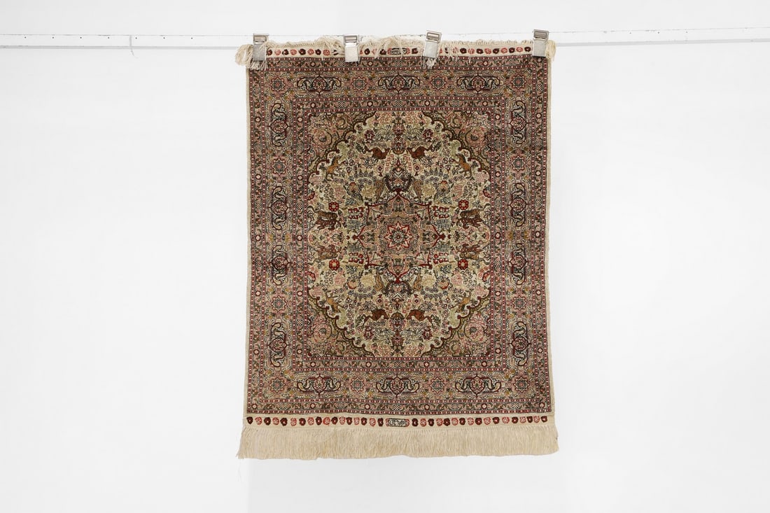 A Persian silk rug,: A Persian silk rug, with a medallion to the centre with animal and foliate motifs, to a buff ground, with natural borders, signed to the centre top and bottom, 77 x 97cm