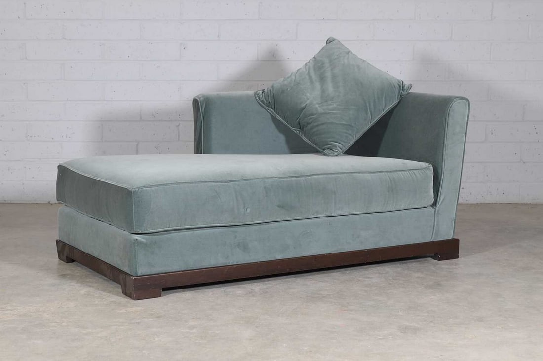A left-hand facing chaise longue,: A left-hand facing chaise longue, of recent manufacture, the green velvet upholstered seat supported on a dark teak wood frame and block feet, with matching cushion, 160cm long 90cm deep 70cm high, se
