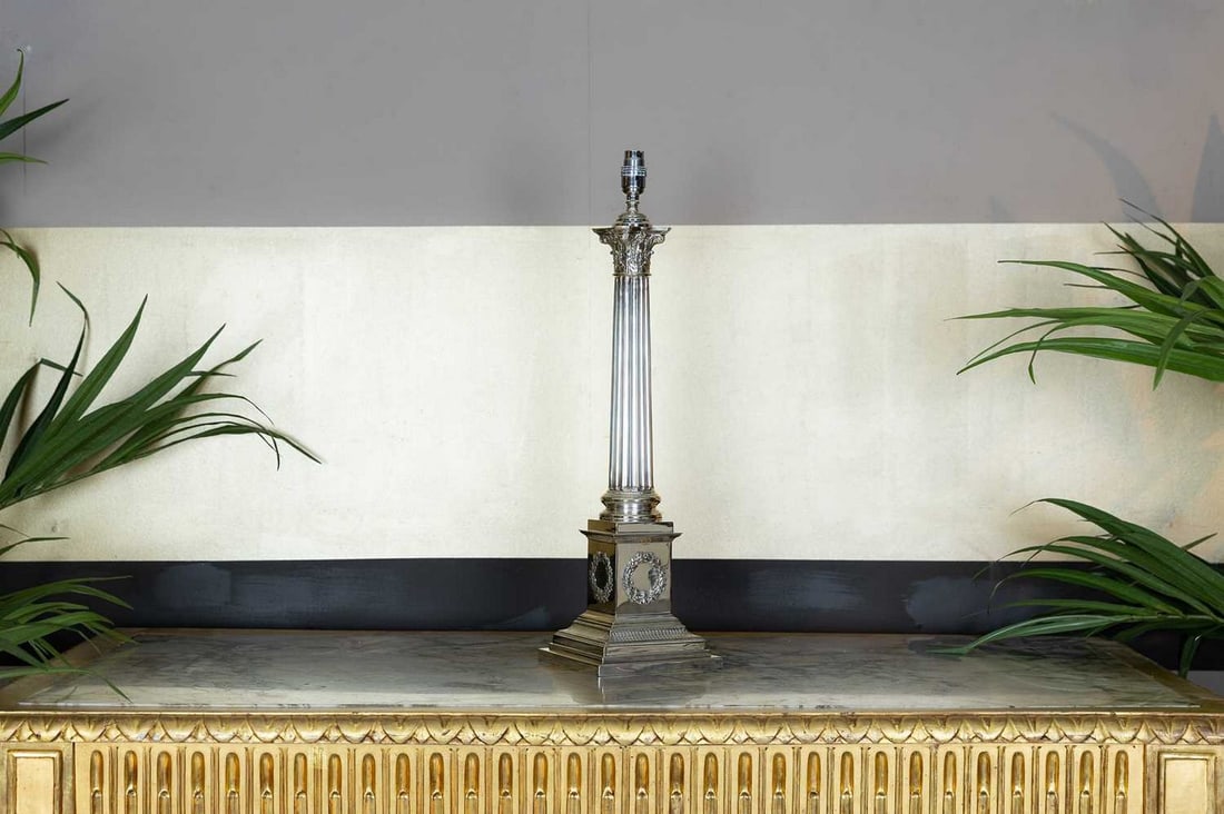 A large silver-plated Corinthian column table lamp,: A large silver-plated Corinthian column table lamp, 20th century, by Mappin & Webb, the fluted column above a square stepped base decorated with a laurel wreath, 17cm wide 17cm deep 53cm high