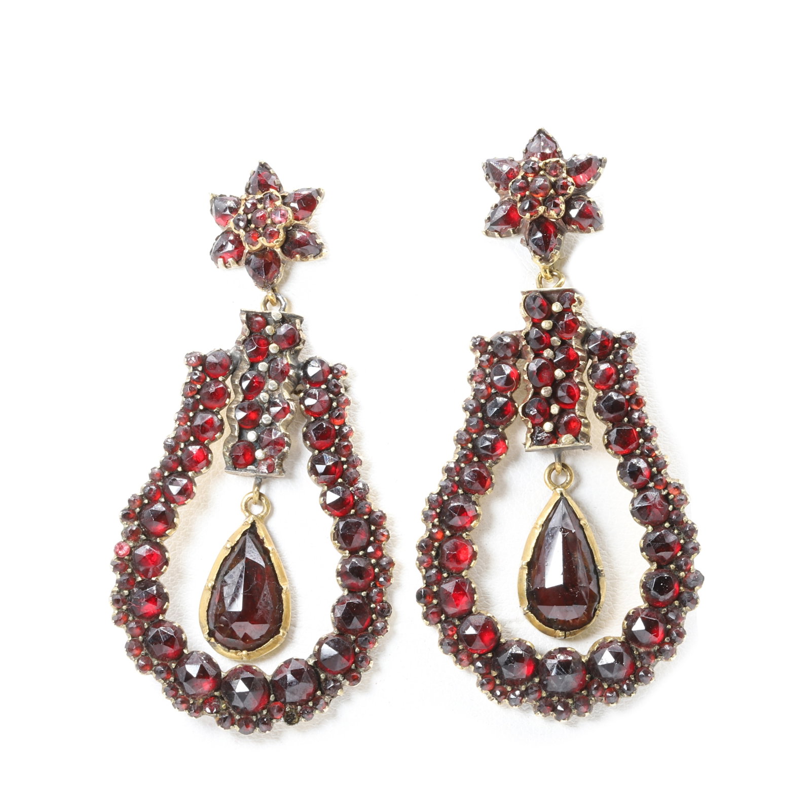 A pair of Bohemian garnet drop earrings,: A pair of Bohemian garnet drop earrings, each earring articulated and set throughout with round and pear shaped faceted garnets, and with a central pear shaped garnet drop, all claw set to gilt metal 