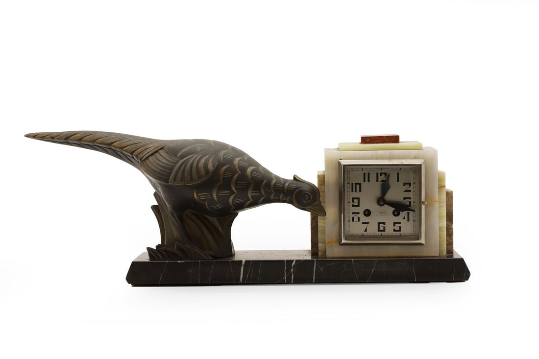 A French Art Deco marble and onyx clock,: A French Art Deco marble and onyx clock, possibly by Irénée Rochard, the square dial with Arabic numerals, with stylized spelter pheasant to the base 43cm wide 18cm high Condition Report: Mi
