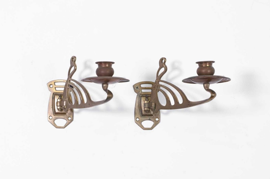 A pair of Art Nouveau brass wall sconces,: A pair of Art Nouveau brass wall sconces, c.1900, each of scrolling form, 21cm long 7cm wide 13cm high (2) Provenance: The collection of Charles Edwards and Julia Boston, Tile Barn, Northamptonshire.