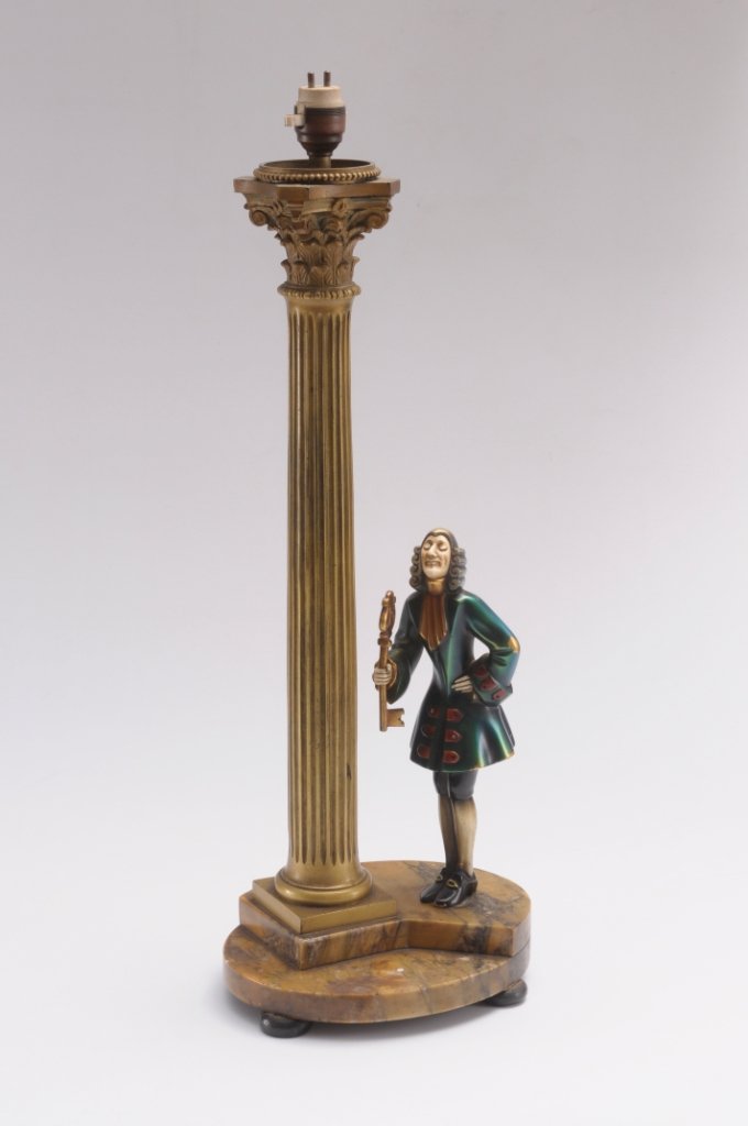 Roland, Paris, an Art Deco bronze table lamp, mode: Roland, Paris, an Art Deco bronze table lamp, modelled as a Corinthian column lamp, with a cold painted gentleman holding a key, with ivory face and hands, on a stepped oval marble plinth and bun feet