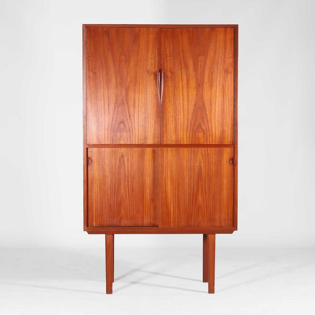 Attributed to Henry Rosengren Hansen (Danish, 1899-1978),: Attributed to Henry Rosengren Hansen (Danish, 1899-1978), a teak drinks cabinet, c.1960, the pair of doors opening to reveal a mirrored interior with a pull-out shelf, over a pair of sliding cupboard