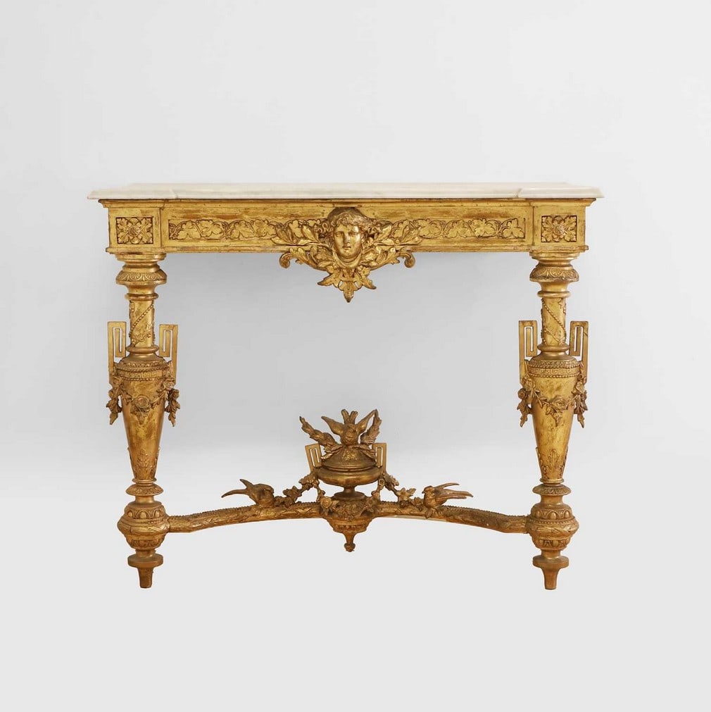 A marble and gilt console table,: A marble and gilt console table, late19th/early 20th century, the carved and giltwood stand centred with a mask and with an ivy leaf frieze, all raised on tall vase-shaped supports with garland mounts