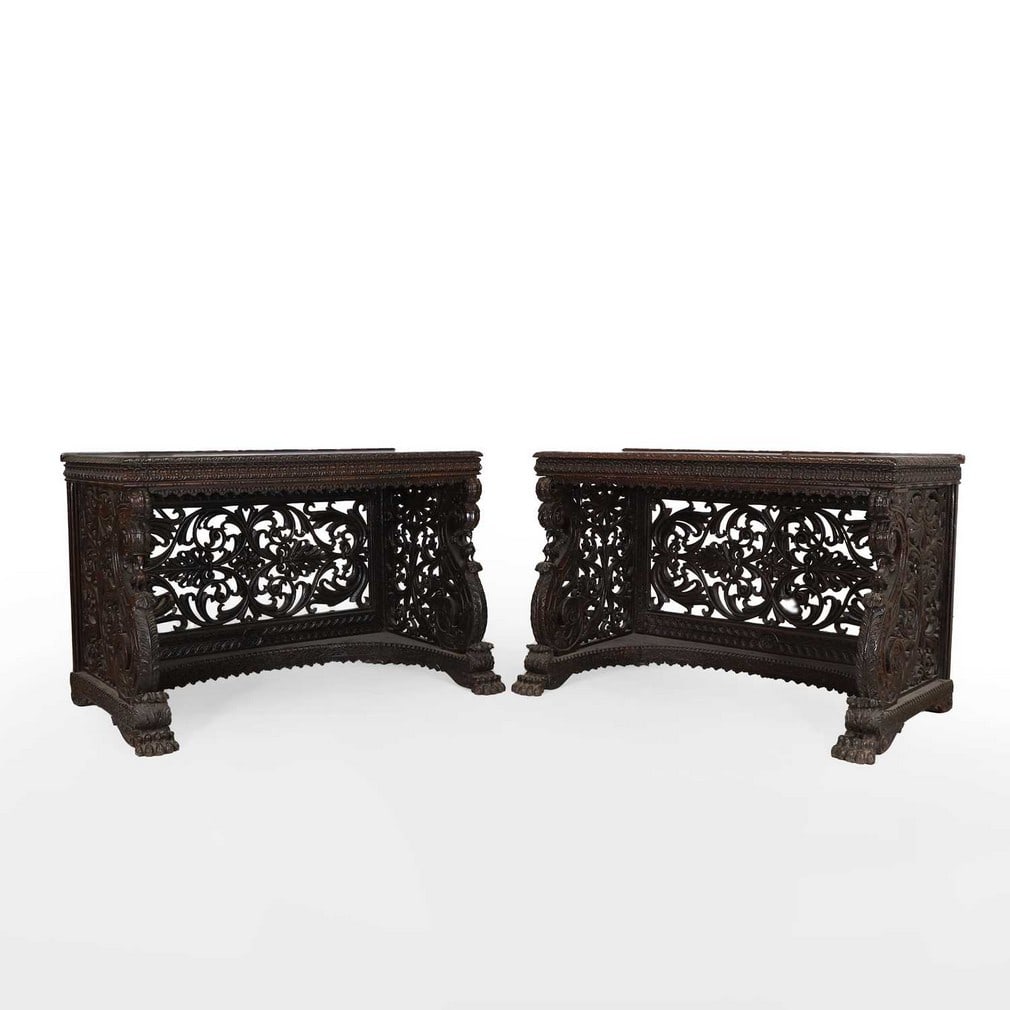 A pair of rosewood console tables,: A pair of rosewood console tables, mid-19th century, Anglo-Indian, each with a rectangular top with a low raised gallery and foliate-carved moulding, above a foliate-carved frieze, raised on scrolling