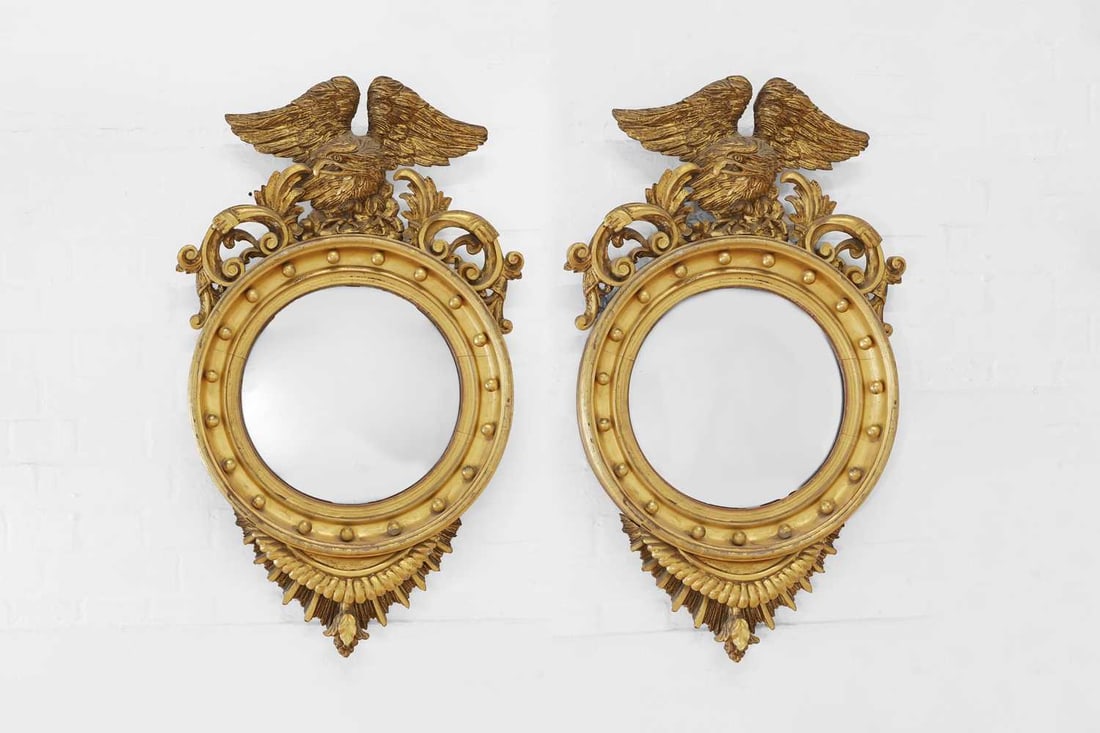 A pair of giltwood convex mirrors,: A pair of giltwood convex mirrors, 19th century and later, each mirror with an eagle surmount with foliate scrolls, the frame decorated with balls to the slip and enclosing a later glass plate, 65cm d