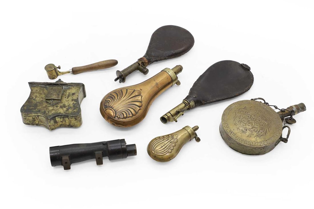 A group of powder flasks: A group of powder flasks 19th century, comprising three leather examples, largest 22cm, a copper example, embossed with a shell, 19cm long, a similar smaller brass example, 10.2cm long, and two Ottoma