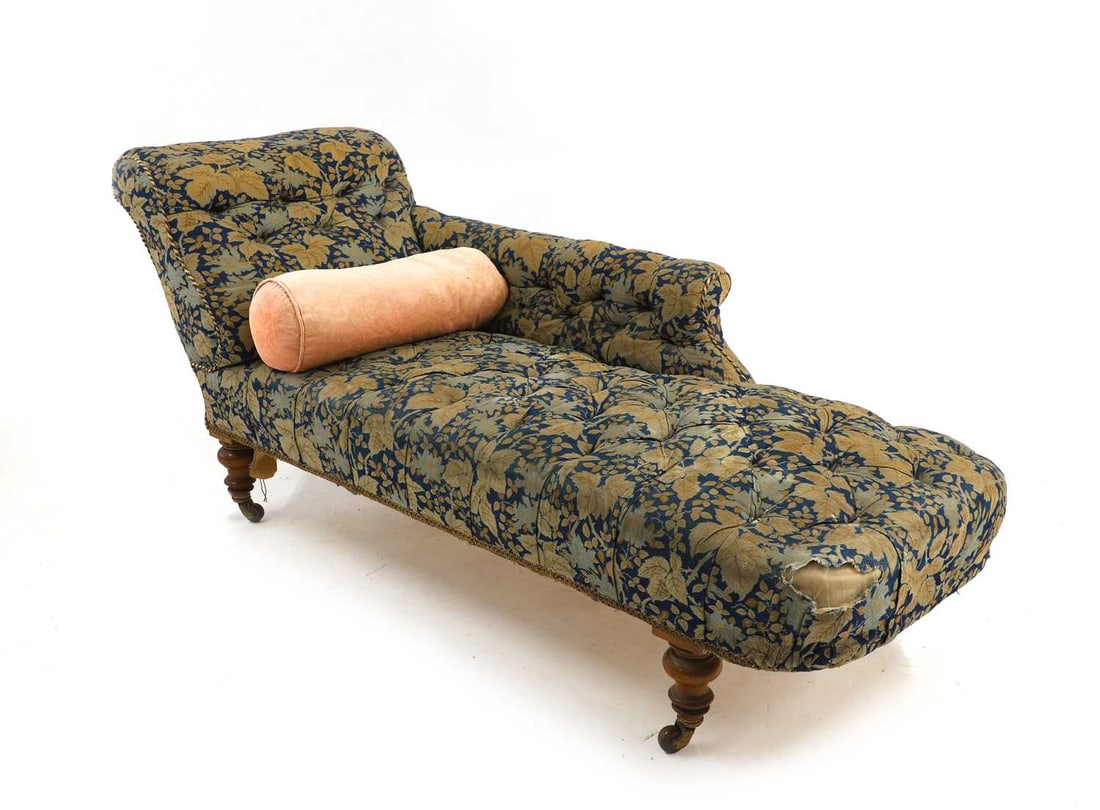 A Victorian chaise longue: A Victorian chaise longue late 19th century, with deep button upholstery and scroll end, on turned walnut legs, one stamped '50779', terminating in bakelite castors, 143cm wide 61cm deep 73cm high Con