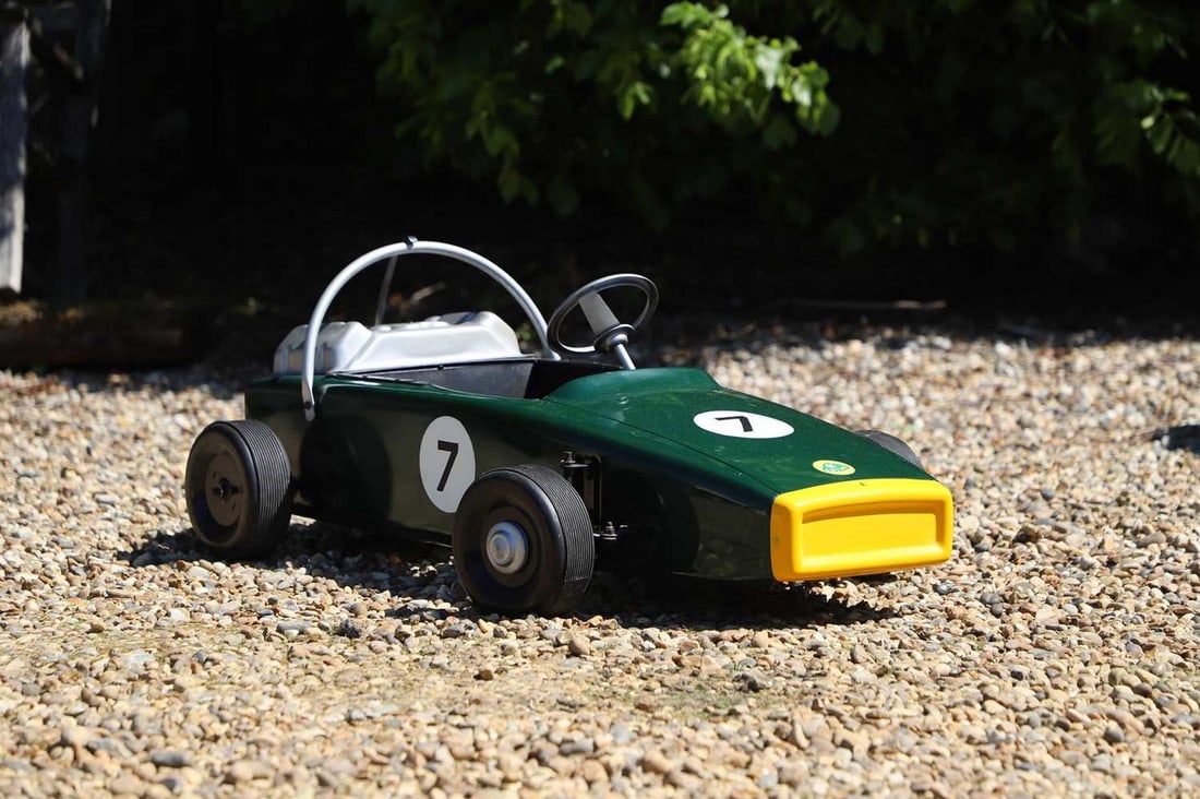 A 1960s Lotus pedal car,: A 1960s Lotus pedal car, finished in Formula One 'Lotus 7' paint scheme after the iconic racing car, fitted with a wide set of tyres, roll hoop and tin engine cowling, 114cm long 39cm wide bodywork