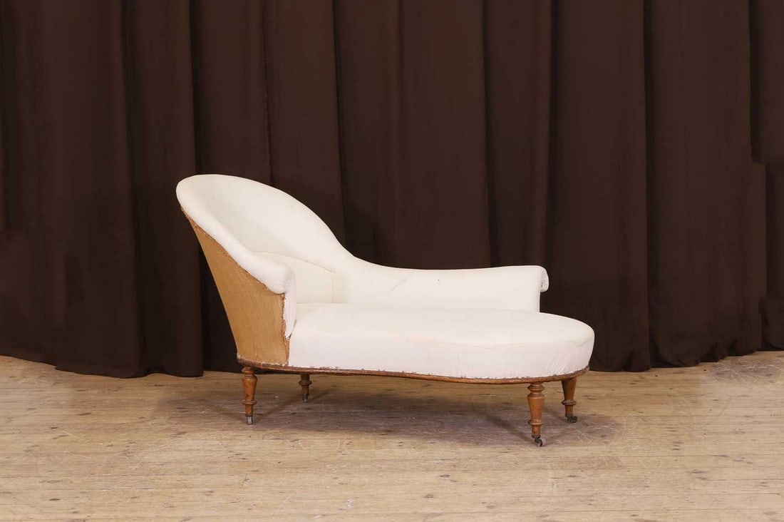 An upholstered chaise longue,: An upholstered chaise longue, second half of the 19th century, French, with a high back and scroll arms, raised on tapering, turned walnut supports and castors, 164cm long 75cm wide 95cm high Conditio